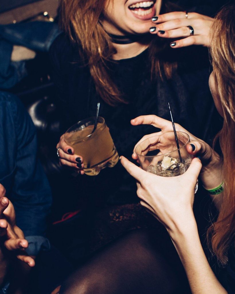 two women talking while holding drinking glasses